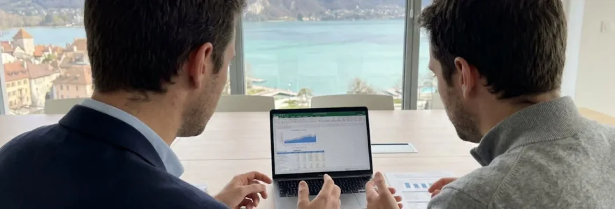 Deux professionnels collaborant autour d'un ordinateur portable lors d'une session de travail en séminaire d'entreprise