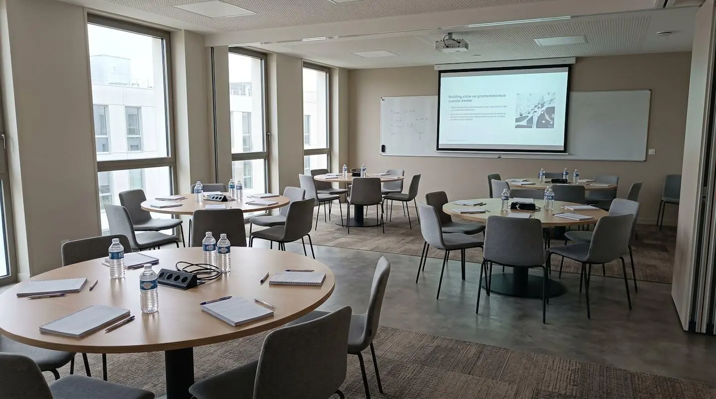 Prise de notes manuscrites lors d'une session de travail en séminaire professionnel, stylo moderne et cahier sur bureau épuré